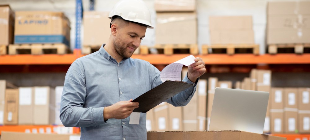 Profissional da área de compras analisando documentos de inventário em um depósito de peças automotivas, representando boas práticas de gestão de estoque na frota pesada