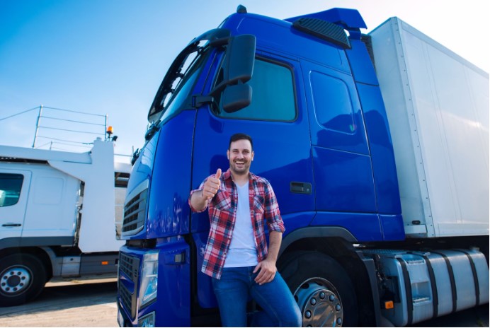 Homem sorrindo e fazendo sinal de positivo enquanto encosta em um caminhão azul, transmitindo confiança e satisfação com a operação da frota.